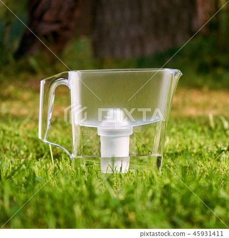 Water filter jug standing on the green grass in summer garden 45931411