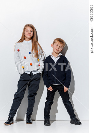 The portrait of cute little boy and girl in stylish jeans clothes looking at camera at studio The portrait of cute little boy and girl in stylish jeans clothes looking at camera at studio 45933593