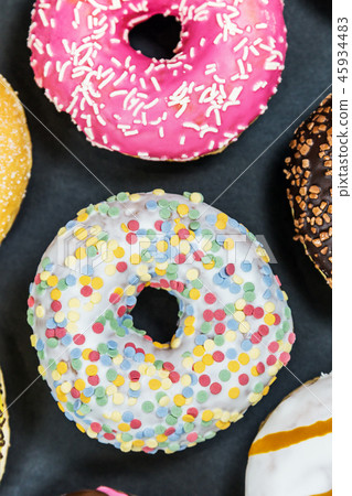 assorted donuts with different fillings and icing on a black bac 45934483