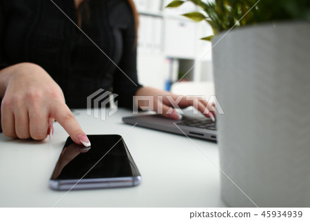 Female arm hold phone and silver pen at workplace closeup Female arm hold phone and silver pen at workplace closeup 45934939