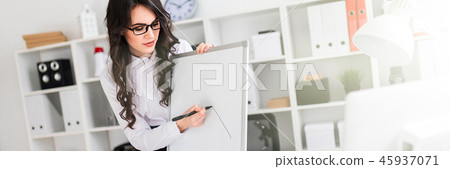 A beautiful young girl stands near an office desk and draws a magnetic marker on the magnetic board. 45937071