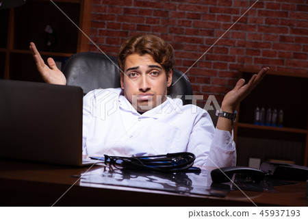 Young handsome doctor working night time at the hospital  45937193