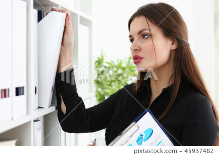 Beautiful brunette female clerk searching for proper document Beautiful brunette female clerk searching for proper document 45937482