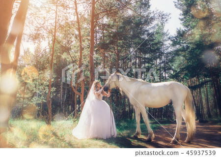 bride stroking the white unicorn in the forest 45937539