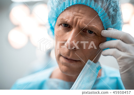 Close up of tired doctor frowning and touching his forehead Close up of tired doctor frowning and touching his forehead 45938457