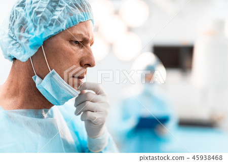 Worried doctor taking off his medical mask and frowning Worried doctor taking off his medical mask and frowning 45938468