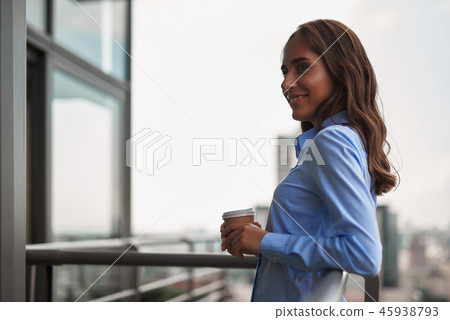 Female worker drinking coffee on office balcony Female worker drinking coffee on office balcony 45938793