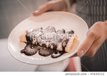 Female waitress holding white plate with pancakes topped with chocolate Female waitress holding white plate with pancakes topped with chocolate 45939132