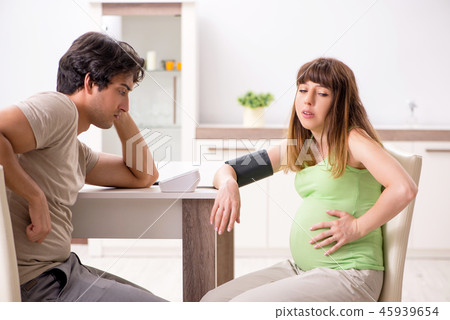 Husband checking pregnant wife's blood pressure 45939654