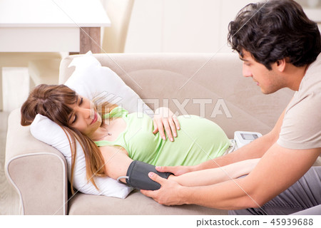 Husband checking pregnant wife's blood pressure 45939688