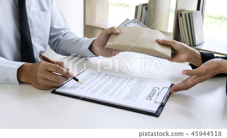 Business woman giving bribe money in a brown envelope while give Business woman giving bribe money in a brown envelope while give 45944518