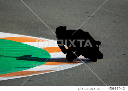 Black motorbike racing pilot tracing curve in circuit Black motorbike racing pilot tracing curve in circuit 45945942