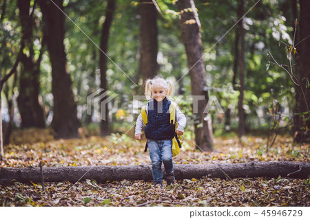 The theme children outdoor activities. Funny little baby Caucasian blond girl walks through forest The theme children outdoor activities. Funny little baby Caucasian blond girl walks through forest 45946729
