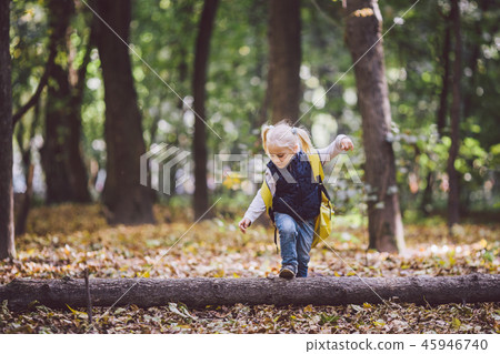 The theme children outdoor activities. Funny little baby Caucasian blond girl walks through forest The theme children outdoor activities. Funny little baby Caucasian blond girl walks through forest 45946740