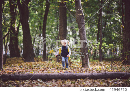 The theme children outdoor activities. Funny little baby Caucasian blond girl walks through forest The theme children outdoor activities. Funny little baby Caucasian blond girl walks through forest 45946750