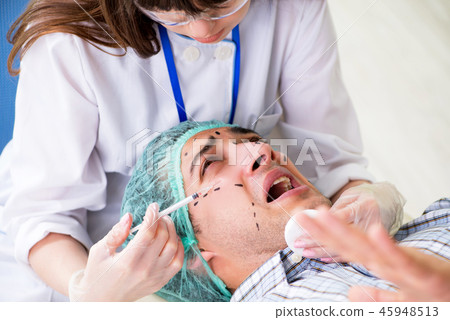 Plastic surgeon preparing for operation on man face Plastic surgeon preparing for operation on man face 45948513