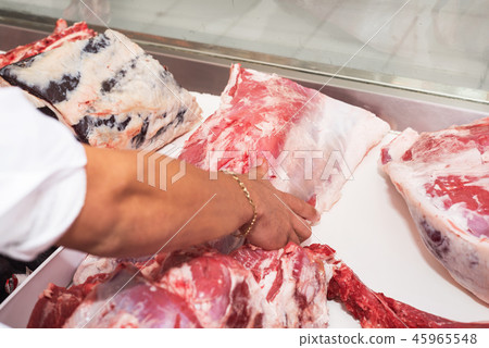 Butcher offering fresh meat at display in butchery Butcher offering fresh meat at display in butchery 45965548