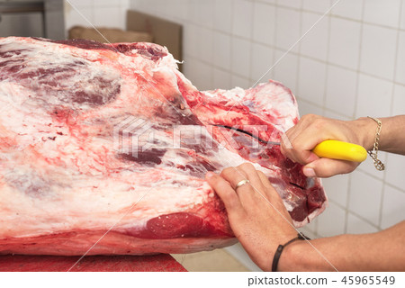 butcher cutting meat in the butchery. Close up butcher cutting meat in the butchery. Close up 45965549