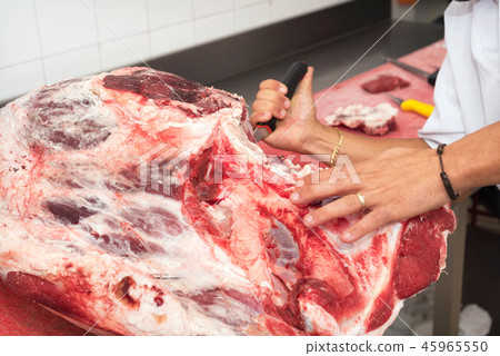 butcher cutting meat in the butchery. Close up butcher cutting meat in the butchery. Close up 45965550