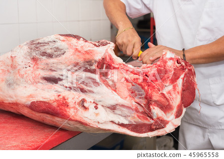 butcher cutting meat in the butchery. Close up butcher cutting meat in the butchery. Close up 45965558