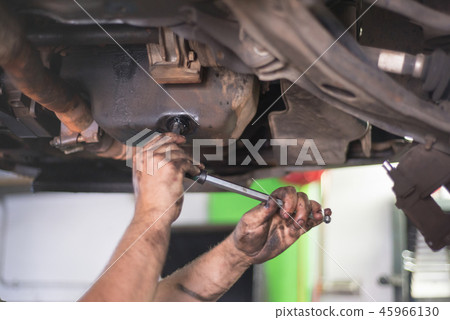 Car mechanic removing used engine oil 45966130
