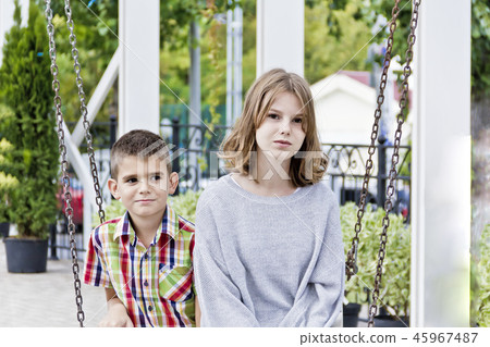 Brother and sister are riding on a swing 45967487