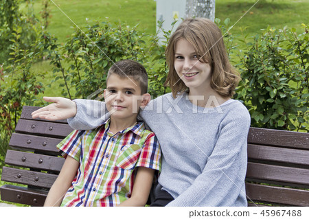 Brother and sister are sitting on bench 45967488