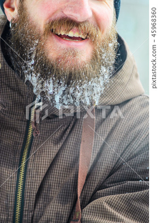 Smiling young man with beard in icicles Smiling young man with beard in icicles 45968360