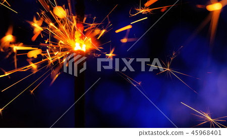 Sparkler Over Blue. Gun powder sparks shot against deep dark background. Burning fuse or bengal fire Sparkler Over Blue. Gun powder sparks shot against deep dark background. Burning fuse or bengal fire 45968401