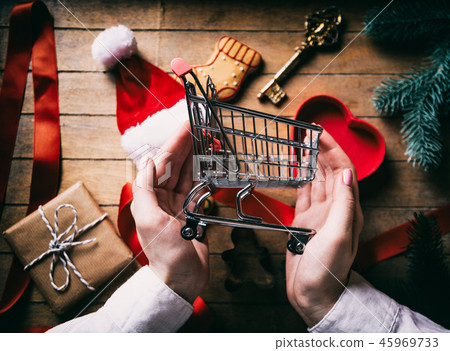 Hands holding Shopping cart with Cristmas gifts Hands holding Shopping cart with Cristmas gifts 45969733