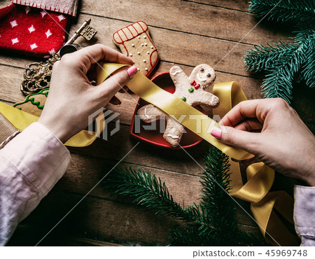 hands wrapping christmas gifts and cookies 45969748