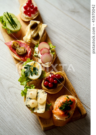 wooden board with colorful healthy mini sandwiches or tapas on a wooden table 45970042