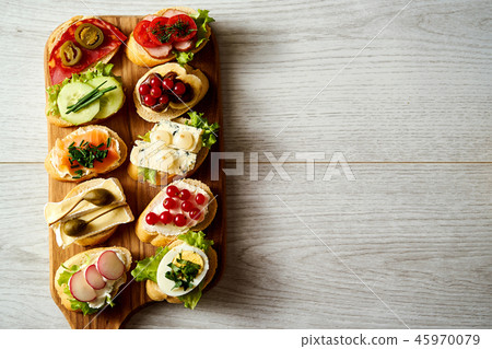 wooden board with colorful healthy mini sandwiches or tapas on a wooden table wooden board with colorful healthy mini sandwiches or tapas on a wooden table 45970079