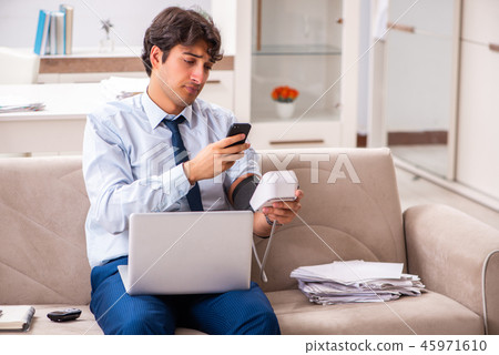 Man under stress measuring his blood pressure 45971610
