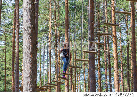 Young brave woman climbing in adventure rope park 45978374