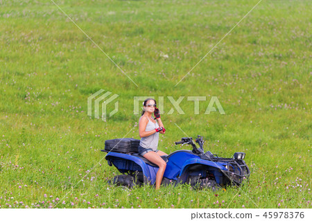 Elegant woman riding quadrocycle on spring field 45978376