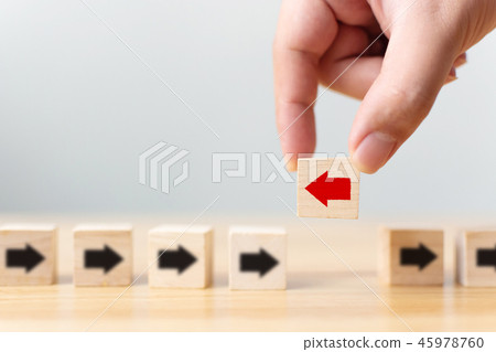 Hand holding wooden block with red arrow facing 45978760