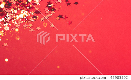 Metallic confetti on festive red paper background. 45985392