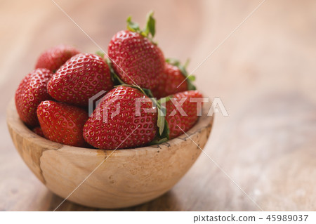 Ripe strawberries in wooden bowl on wood background with copy space Ripe strawberries in wooden bowl on wood background with copy space 45989037