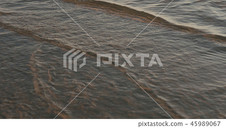 closeup of small waves with caustics on a beach at sunset 45989067