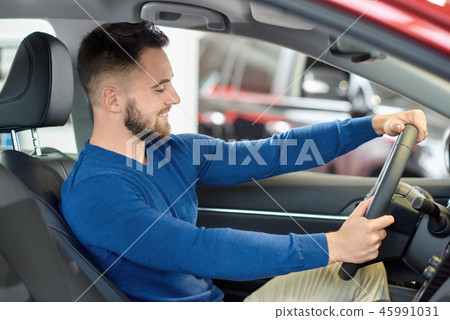 Young visitor of auto salon sitting at front seat in car. Young visitor of auto salon sitting at front seat in car. 45991031