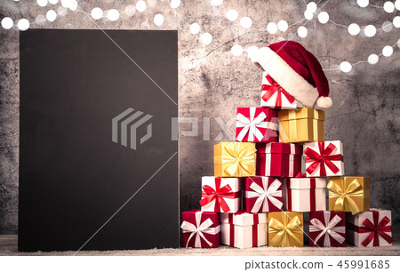Christmas gift boxes in front of concrete wall shape of pyramid with Santa Claus hat on top. View Christmas gift boxes in front of concrete wall shape of pyramid with Santa Claus hat on top. View 45991685