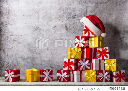 Christmas gift boxes in front of concrete wall shape of pyramid with Santa Claus hat on top. View Christmas gift boxes in front of concrete wall shape of pyramid with Santa Claus hat on top. View 45991686