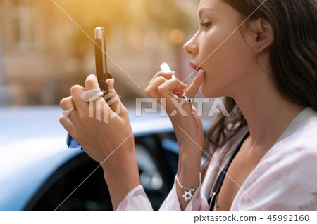 Beautiful woman holding red lipstic and doing quick makeup 45992160