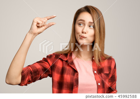 Positive woman shows something very tiny or small 45992588
