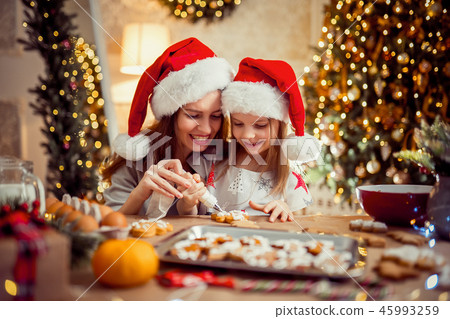 Merry Christmas and Happy Holidays. Mother and daughter cooking Christmas cookies. 45993259