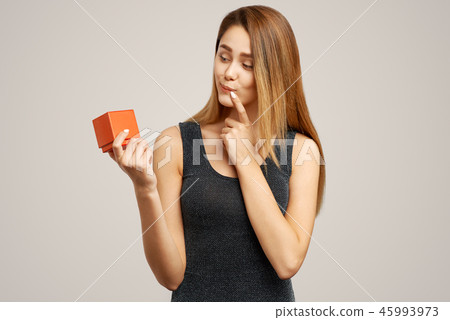 woman looks thoughtfully at a red gift box 45993973