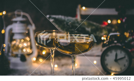 Picture of two champagne glasses on blurred background with Christmas tree, lantern, clock 45995012