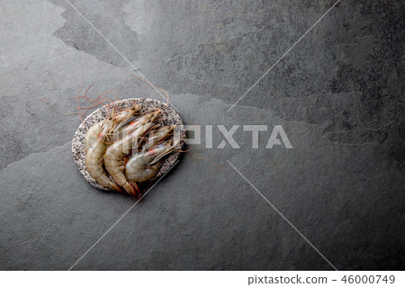 Raw whole fresh uncooked prawns shrimps on stone gray plate, stone background. Top view with copy 46000749