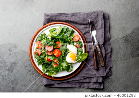 Fresh summer salad with baby spinach, tomatoes cherry and egg. Top view, copy space. Slate gray 46001298
